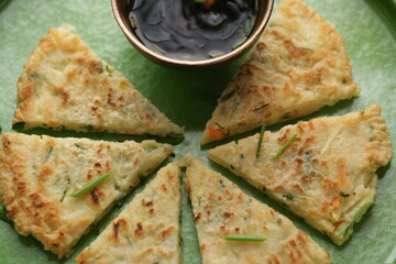 Overhead view of Korean pa jun pancakes and jam on green plate