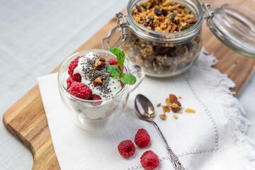 Granola in a jar and in a cup with yogurt and raspberry top view. Granola is a breakfast food and snack food consisting of rolled oats, nuts, honey, that is baked until golden brown