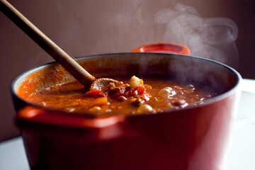 Steaming hot hominy chili in pot with wooden spoon