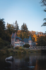 Fototapeta na wymiar Traditionelle deutsches Haus am Ufer eines Flusses, während des Herbst im Harz (Hochformat)