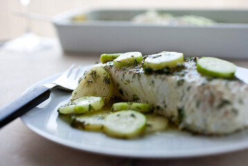 Plate of cooked fish with cucumber slices