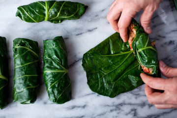 Close up of hands making stuffed collard greens