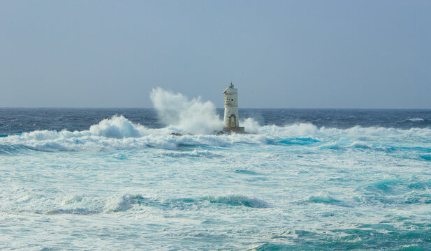 The lighthouse of the Mangiabarche shrouded by the waves of a mistral wind storm
