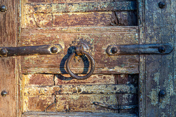 Ancient old metal door handle knocker on a wooden door.
