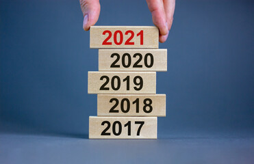 Male hand placing a block with number '2021' on a blocks tower with numbers '2017, 2018, 2019,...
