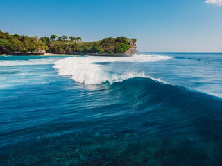 Barrel blue wave in ocean and cliff at background. Aerial view of surfing wave