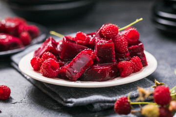 Homemade  raspberry marmalade  in a plate on a  dark background. berries fruit jelly candies.