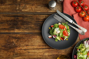 Delicious salad with crab sticks and tomatoes served on wooden table, flat lay. Space for text