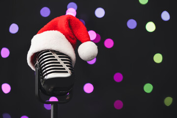 Retro microphone with Santa hat against blurred lights, space for text. Christmas music