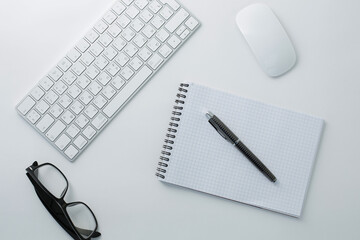 Glasses keyboard mouse notepad and pen on white background