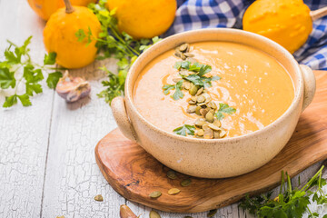 Pumpkin soup with roasted pumpkin seeds on white wooden table, top view, copy space. Seasonal autumn food