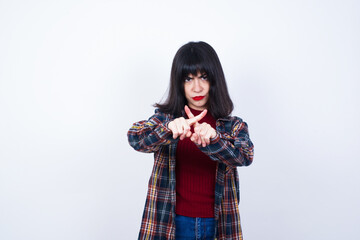 Beautiful young Caucasian woman standing against white background has rejection angry expression...