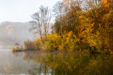 Obraz premium Beautiful landscape with lake and forest. Amazing nature wallpaper. Autumn trees in foggy morning. Romantic place. 