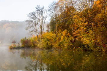 Beautiful landscape with lake and forest. Amazing nature wallpaper. Autumn trees in foggy morning. Romantic place. 