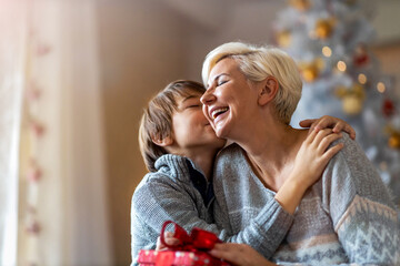 Happy son giving mother Christmas gift
