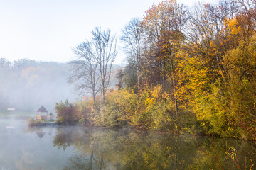 Beautiful landscape with lake and forest. Amazing nature wallpaper. Autumn trees in foggy morning. Romantic place. 