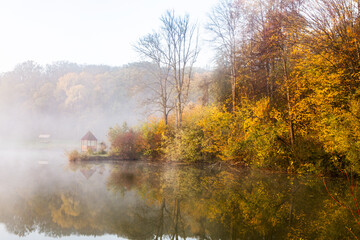 Beautiful landscape with lake and forest. Amazing nature wallpaper. Autumn trees in foggy morning. Romantic place. 