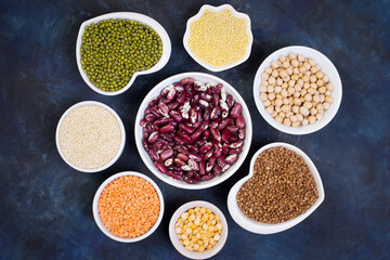 Variety of cereals and legumes on a dark background. Lentils, red beans, quinoa, chickpeas, mash, split peas, millet, buckwheat. Gluten-free products. Top view.