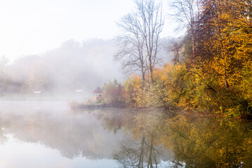 Beautiful landscape with lake and forest. Amazing nature wallpaper. Autumn trees in foggy morning. Romantic place. 