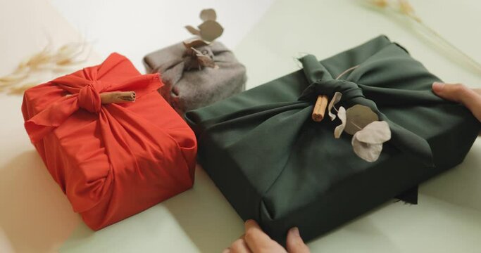 Young female hands organizing gifts wrapped in cloth, Christmas and New year minimalist concept. 4k