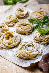 Pasta alluovo, Tagliatelle or fettuccine. Round balls of raw pasta on the wooden cutting board on black background