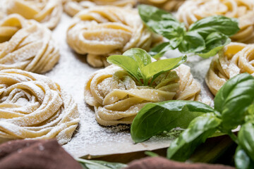 Pasta alluovo, Tagliatelle or fettuccine. Round balls of raw pasta on the wooden cutting board on black background