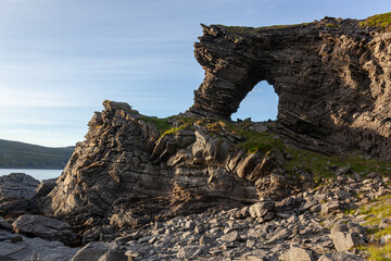 Natural arch in the Rock Kirkeporten with view to the Barents sea and Mageroya island, Skarsvag, Northern Norway