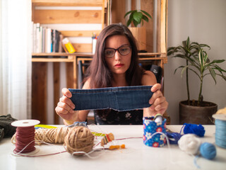 Young Attractive Hispanic Woman in Black Dress Sews Face Mask with Thread and Piece of Cloth