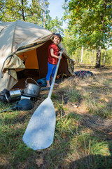 Boy playing with paddle near tent in camping site and having fun
