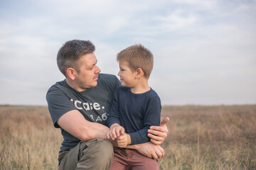 Happy son hugging dad on the  meadow background. Concept of father-son relationship
