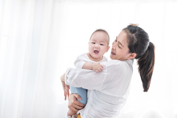 Asian woman smile and holding son baby in her arms. Happy family. Asia mother lifting and looking her adorable kid baby on white. love people concept