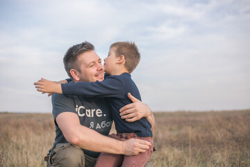 Happy son hugging dad on the  meadow background. Concept of father-son relationship