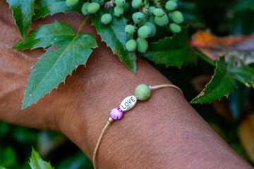 outdoor closeup of a hand wearing tiny jewelry bracelet with mineral bead stone