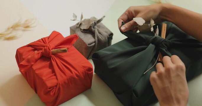 Young female hands setting up gifts wrapped in cloth on the table, Christmas and New year minimalist concept. 4k