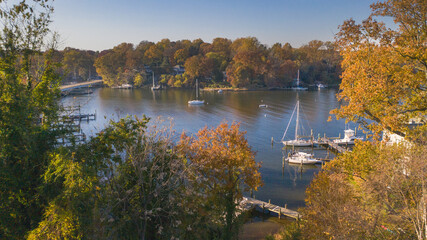 Aerial view of colorful sailboat moorings, docks,   and bright golden foliage on Weems Creek, in...