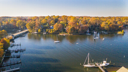 Aerial view of colorful sailboat moorings, docks,   and bright golden foliage on Weems Creek, in...