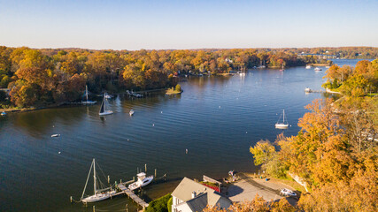 Aerial view of colorful sailboat moorings, docks,   and bright golden foliage on Weems Creek, in...