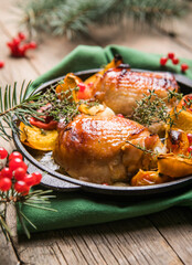 Fototapeta na wymiar Roasted Christmas Chicken thighs with pumpkin for Christmas Dinner. Festive decorated wooden table