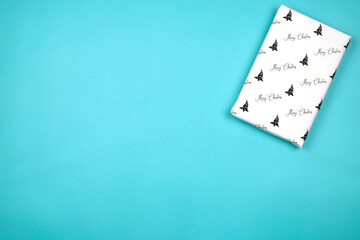 Xmas present wrapped in paper with festive prints. Christmas gift on white background. Homemade bright Christmas present box