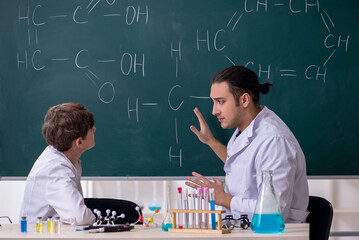 Young chemistry teacher and schoolboy in the classroom