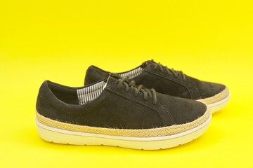 New women's black natural suede sneakers on yellow background, top view
