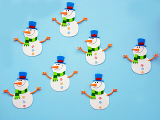 Happy Snowman toy made of paper, on a blue background. Handmade work. Snowflakes, space for text, shot from above, new year and Christmas Concept.