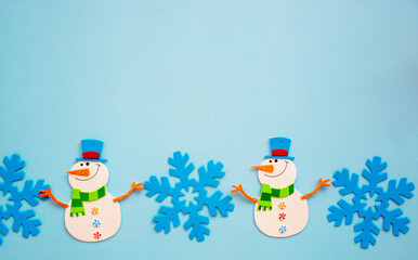 Happy Snowman toy made of paper, on a blue background. Handmade work. Snowflakes, space for text, shot from above, new year and Christmas Concept.