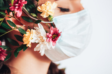 Fototapeta na wymiar Young woman wearing a medical mask made of flowers during a pandemic.