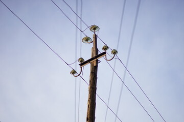 old wooden pillar with wires on clear blue sky background.