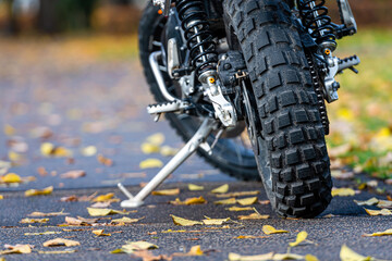sports motorcycle parked on the sidewalk in the park with yellow autumn leaves in the background