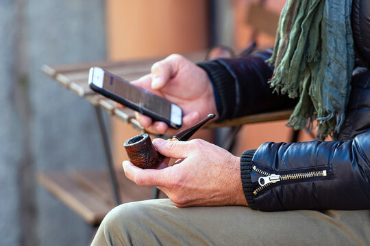 smoking pipe and smartphone in male hands