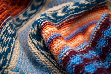 Knitted background. Textile background in blue and white, red, orange and beige colors. Fabric folds.
