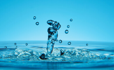 Water drop falling down. Abstract blue background.