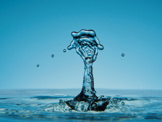 Water drop falling down. Abstract blue background.